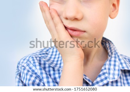 kid, a schoolboy holds his hand on the lower jaw, wrinkles from toothache, the concept of pediatric dentistry, treatment of milk teeth, oral care Royalty-Free Stock Photo #1751652080