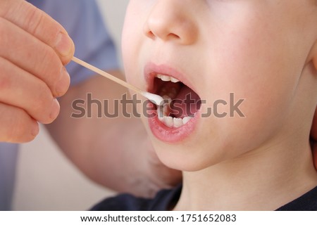 doctor takes a cotton bud from child’s mouth to analyze the saliva, mucous membrane for DNA tests, COVID-19, to determine paternity or presence of virus, concept Royalty-Free Stock Photo #1751652083
