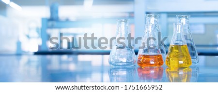 orange yellow solution in science glass flask win blue chemistry laboratory banner background Royalty-Free Stock Photo #1751665952