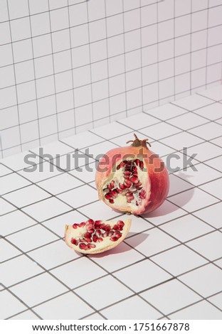 Red pomegranate on a checkered pink background. Concept template food blog, social media, diet concept. Conceptual minimalistic photography of fruit. Copy space