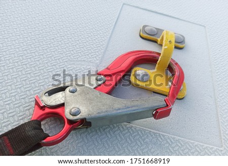 Safety concept at work at height. Red hook clamped for yellow anchor point. Professional PPE for climbing. Close up.