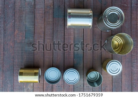 Ecological concept with recycling symbol in the center and wooden background. Food tins.