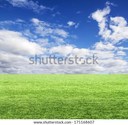 Green field under blue clouds sky.
