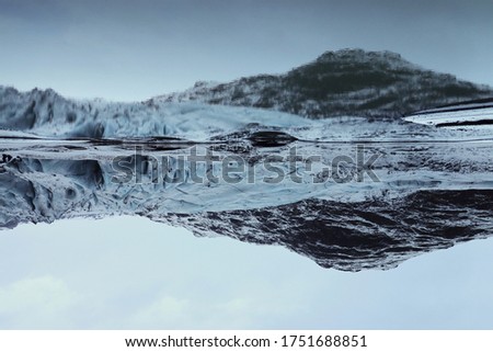 A reversed picture of a glacier with its reflection in water in Iceland during winter