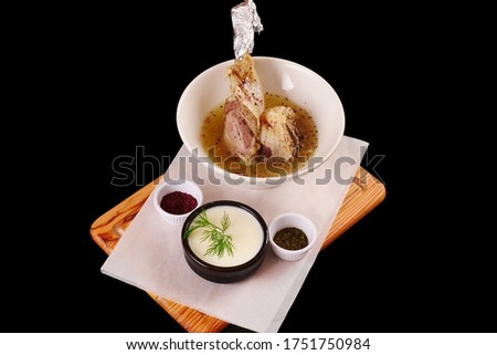 Beef soup. Stock cooked from meat on a bone. Broth, served with a yogurt and spices. Black background.