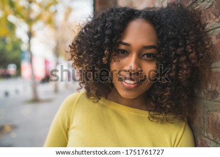 Portrait of beautiful young afro-american woman with curly hair standing outdoors in the street.