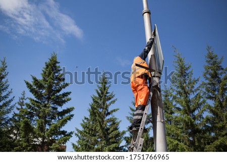 Installation road sign on pole. Road worker sets sign.