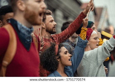 Group of multiethnic people protesting outdoors with placards and signs. People shouting with banners protest as part of a climate change march. Protestors holding worker rights banners at protest. Royalty-Free Stock Photo #1751770574