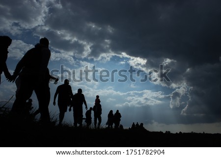 Sun rays illuminate people. Immigration of people. Blue sky with dark clouds Royalty-Free Stock Photo #1751782904