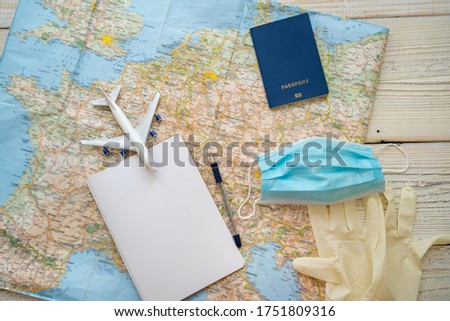 Travel in epidemic quarantine notes template. Table top view with map, plane, notebook, face mask, passport, medical gloves. personal hygiene and protection items in tourism theme. restrictions Royalty-Free Stock Photo #1751809316