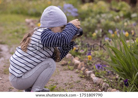 child girl picked up a camera, taking pictures of flowers