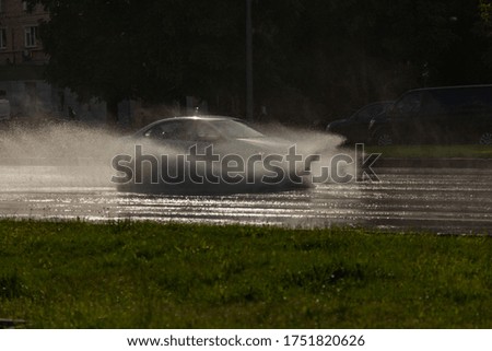MOSCOW, RUSSIA, - June 04, 2020: A passenger car rides on a wet road at high speed. Big splashes fly from under his wheels
