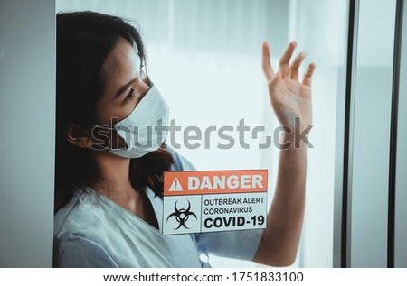 Beautiful woman is treating the coronavirus or Covid-19 in the sterile room of the hospital. She waiting and hope will soon doctor to help patients safely while undergoing detention. Danger sign.