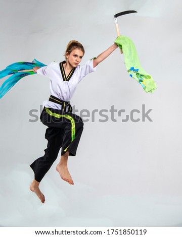 beautiful girl in white does kung fu training poses with battle axes