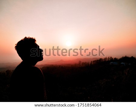 Silhouette of a lonely person in nature. The shadow of a lonely person in the twilight evening. In the dim light, the shape of the face has revealed an endless beauty.