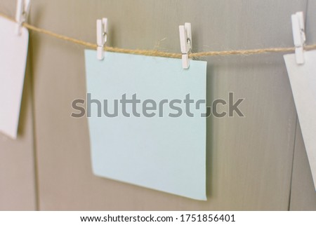 Three multi-colored sheets of paper on a background of a window on clothespins. In the sun. Close-up.