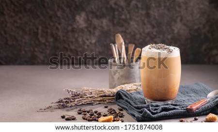 Latte or cappuccino with milk foam and lavender in a glass with coffee beans. Dark background Royalty-Free Stock Photo #1751874008