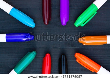 Multi-colored markers on a black wooden background. Top view. Copy space.