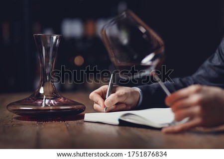 Sommeliers male tasting red wine and making notes aroma degustation card. Royalty-Free Stock Photo #1751876834