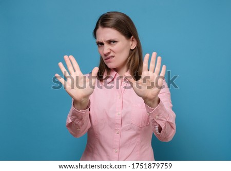 Serious young caucasian woman showing stop gesture with her hand. Social distance concept