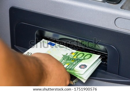 Depositor withdraws EURO from ATM cash money machine. Man hand holding EURO banknotes at the ATM machine Royalty-Free Stock Photo #1751900576