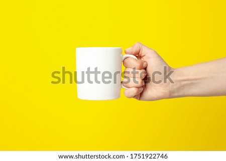 Female hand holding white cup on yellow background, space for text Royalty-Free Stock Photo #1751922746