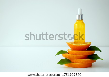 Vitamin C serum in cosmetic bottle on top of orange citrus slices with green leaves on white background. Citrus essential oil, cosmetics aromatherapy. Organic SPA cosmetics with herbal ingredients. Royalty-Free Stock Photo #1751929520