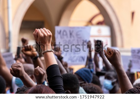 People raising fist with unfocused background in a pacifist protest against racism demanding justice Royalty-Free Stock Photo #1751947922
