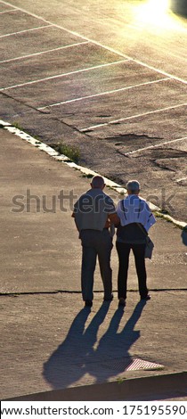 a couple of senior catches holding hands while walking in the street during the sunset , concept of love.