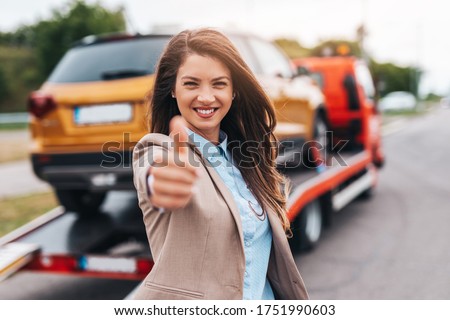 Elegant middle age business woman is happy and satisfied with fast and reliable towing service for help on the road. She showing thumb up. Roadside assistance concept. Royalty-Free Stock Photo #1751990603