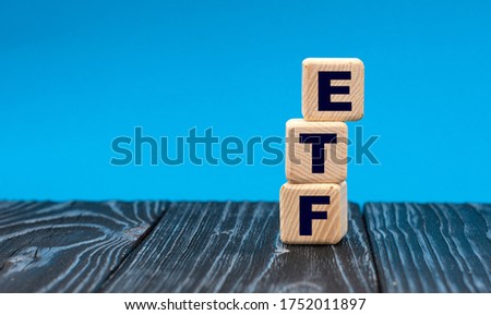 concept word ETF on wooden cubes on a blue background. Technology concept