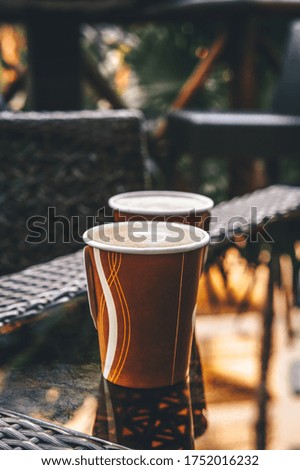 Paper cups with coffee in an outdoor cafe. Friends meeting, time outdoor, ecology concept. Toned image with place for text