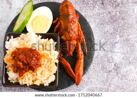 A flatlay picture of "nasi lemak" fresh water lobster "sambal" or spicy sauce on stone table.