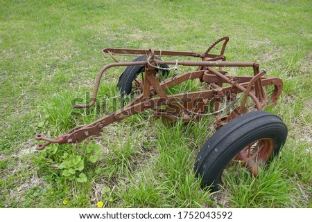 Rusty old farm plow equipment abandoned in grassy field
