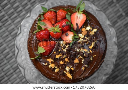Homemade vegan chocolate cake with strawberry, chocolate and cashew nut on top