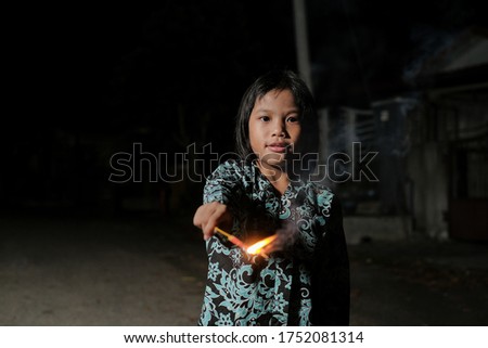 Malay girl celebrating Hari Raya Aidilfitri playing firework in hand