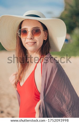 Woman in red bikini smiling at beach.
