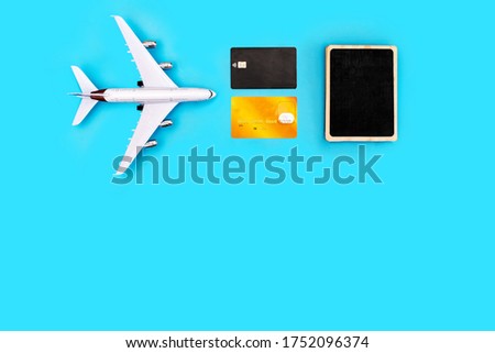 plane, credit cards, and a sign for writing on a blue background. The picture symbolizes the vacation planning and the cost of air travel