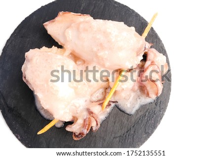 A close up and copyspace picture of "ketupat sotong" on slate table white background. Glutinous rice stuffed in squid that is famous East Coast of Malaysia.