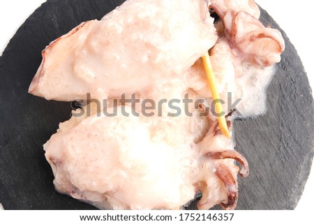 A close up picture of "ketupat sotong" on slate table white background. Glutinous rice stuffed in squid that is famous East Coast of Malaysia.