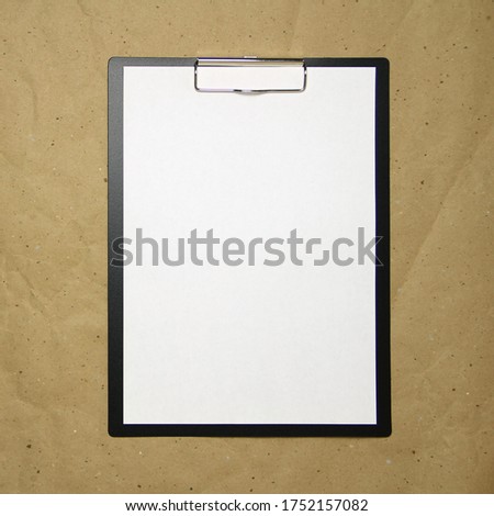 A tablet with a white sheet of A4 format on a beige craft paper. Concept of new opportunities, ideas, undertakings, innovations. Stock photo with empty place for your text and design.