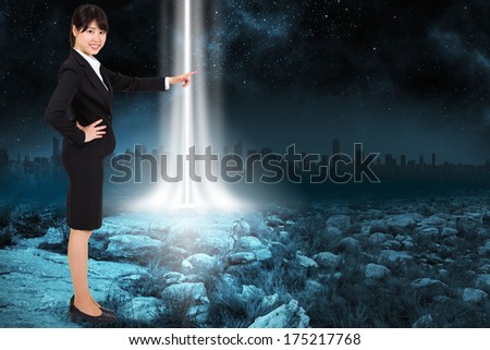 Smiling businesswoman pointing against rocky landscape with light beam