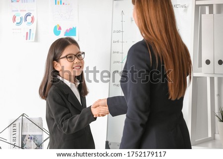 Cute little businesswoman with client shaking hands in office