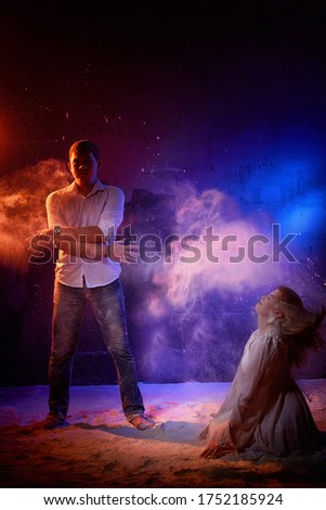 Beautiful young couple during a photo shoot with flour in a dark Studio. A young man and a girl pose together on a black background. Portrait photos of a couple in love. Wedding photo