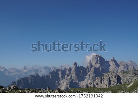 Around hut and peak Tre Cime, Dolomites, Italy. Panorama with rocky peaks, green meadow and blue sky.