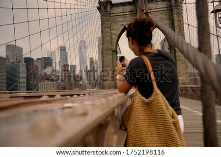Woman in New York city taking picture of the Brooklyn Bridge