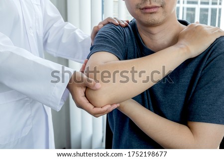 Female physiotherapists provide assistance to male patients with elbow injuries examine patients in rehabilitation centers. Physiotherapy concepts. Royalty-Free Stock Photo #1752198677