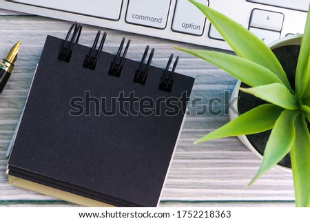 Flat lay and Business Concept.  Fountain pen, keyboard, decorative plant and notepad on wooden background. Copy space