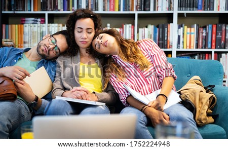 Group of young tired students studying, learning for exam in library