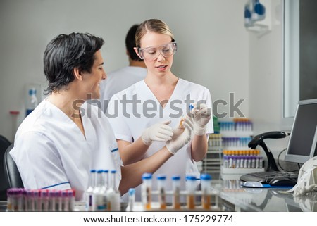 Male and female technicians analyzing sample in medical lab
